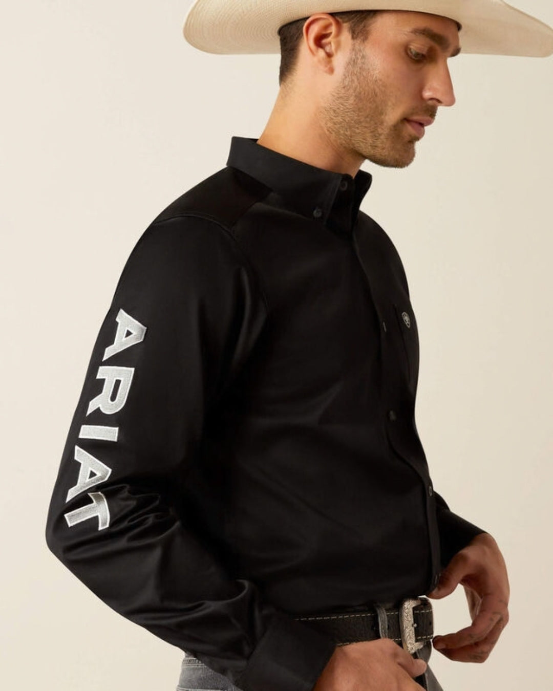Side view of the Ariat Team Logo black twill shirt showing the large white Ariat logo down the sleeve