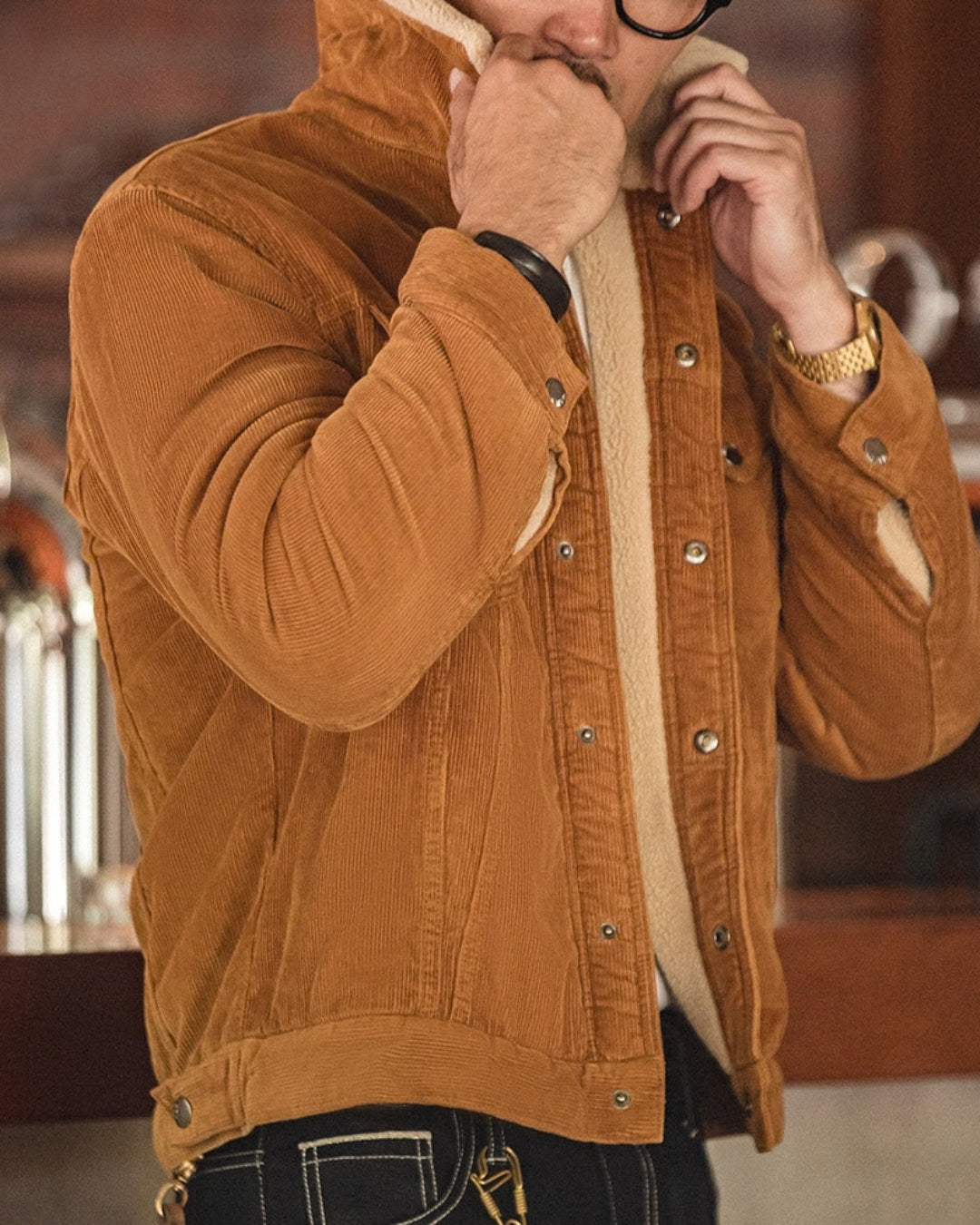 Man turning up the sherpa collar of a tan corduroy barn jacket for extra warmth