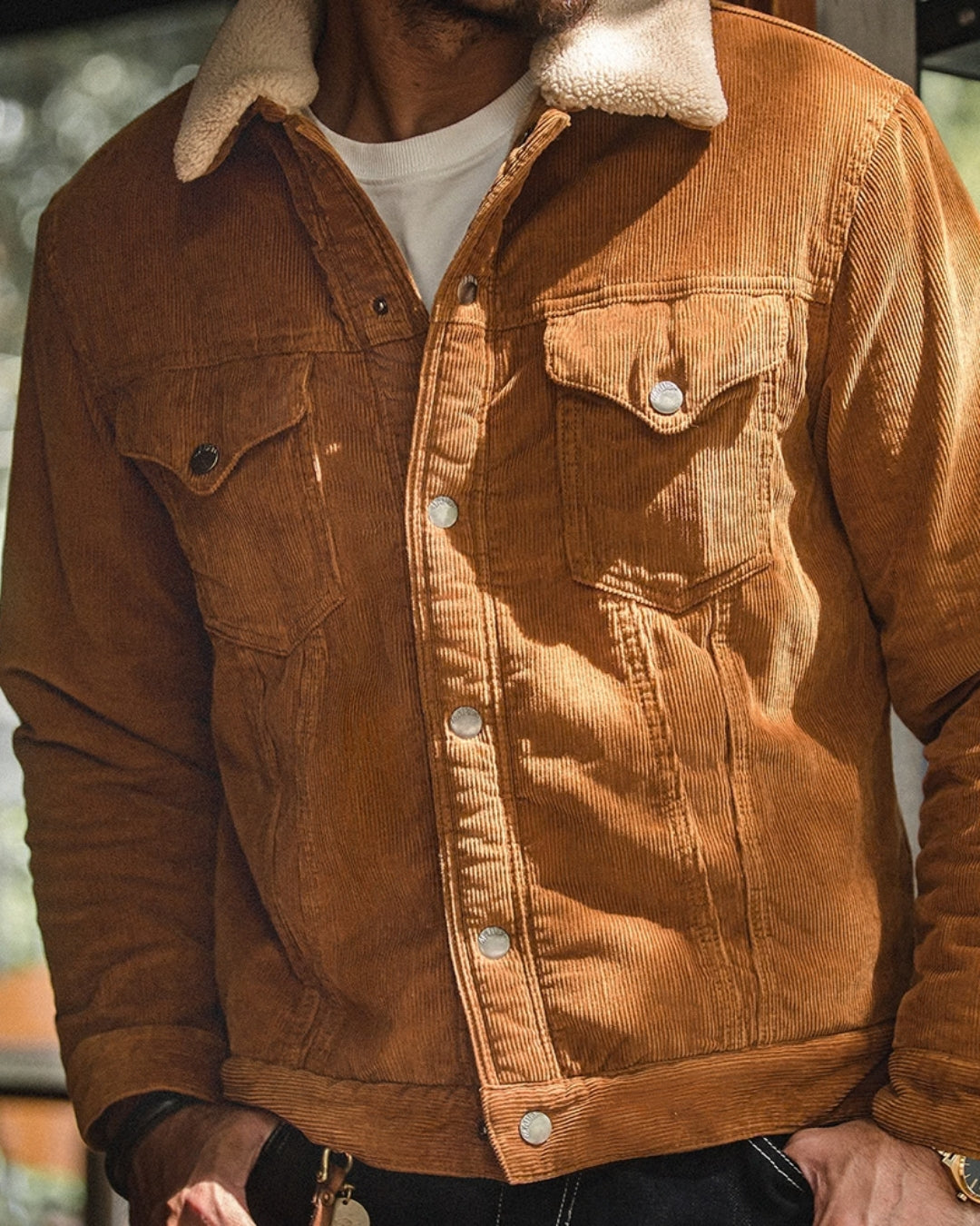 Man wearing a buttoned tan corduroy barn jacket with snap front, chest flap pockets and sherpa collar